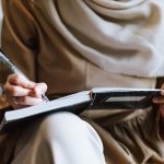 Vrouw die peinzend schrijft in een notitieboek in een café