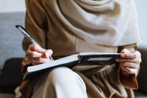 Vrouw die peinzend schrijft in een notitieboek in een café