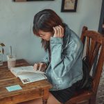 Jonge vrouw schrijft in notitieboekje aan een tafeltje in een café