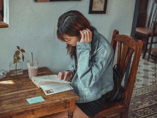 Jonge vrouw schrijft in notitieboekje aan een tafeltje in een café