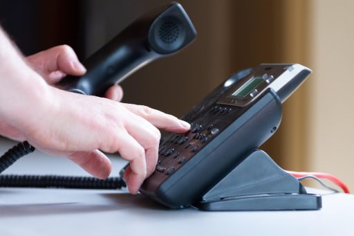 Een ondernemer die twijfelend naar zijn telefoon kijkt voor een belangrijk zakelijk gesprek