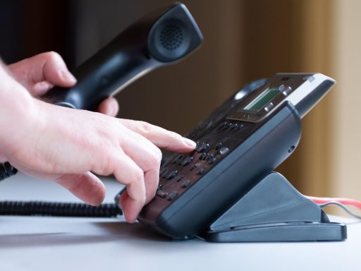 Een ondernemer die twijfelend naar zijn telefoon kijkt voor een belangrijk zakelijk gesprek