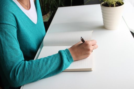 Vrouw schrijft notities aan haar bureau tijdens haar eerste weken in een nieuwe job