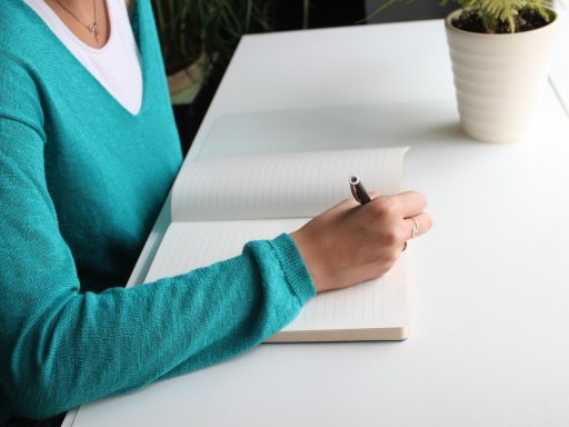 Vrouw schrijft notities aan haar bureau tijdens haar eerste weken in een nieuwe job