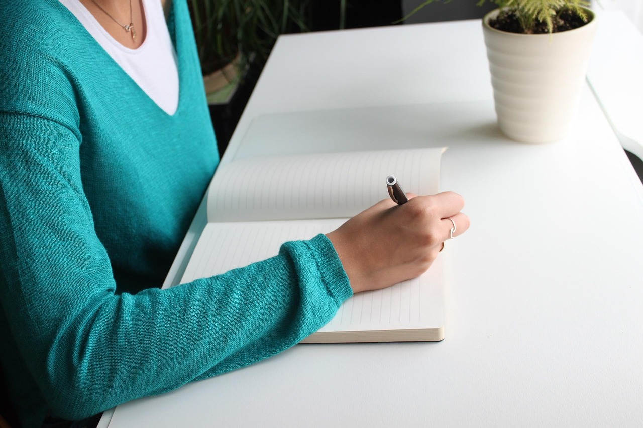 Vrouw schrijft notities aan haar bureau tijdens haar eerste weken in een nieuwe job