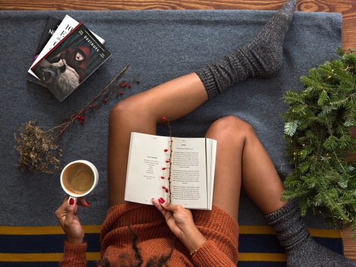 Een vrouw leest geconcentreerd een boek met een kop koffie naast haar, een beeld van rustige zelfontwikkeling op latere leeftijd