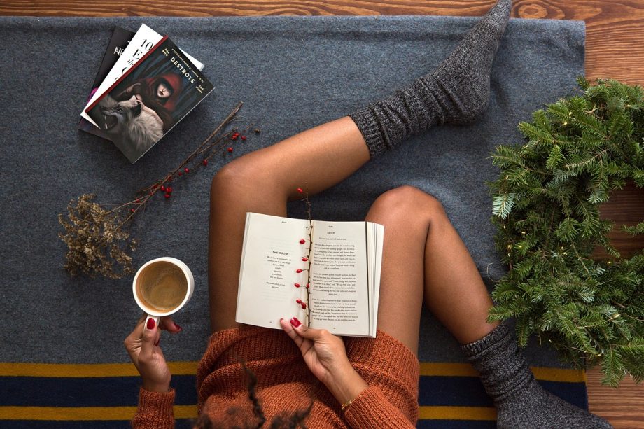 Een vrouw leest geconcentreerd een boek met een kop koffie naast haar, een beeld van rustige zelfontwikkeling op latere leeftijd