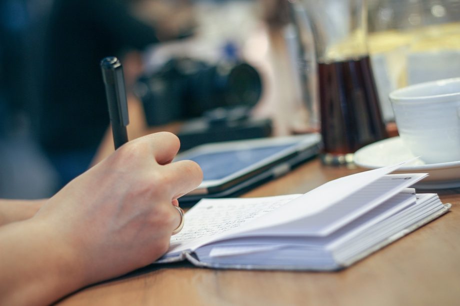 Persoon schrijft motiverende teksten in een notitieboek aan een bureau