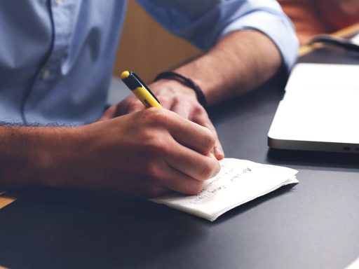 Persoon die aantekeningen maakt aan een bureau tijdens het sollicitatieproces