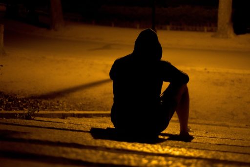Persoon die alleen zit en nadenkend voor zich uitkijkt