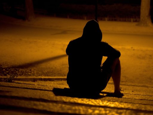 Persoon die alleen zit en nadenkend voor zich uitkijkt