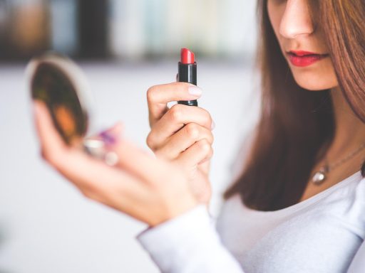Vrouw met grijs haar die make-up aanbrengt voor een spiegel